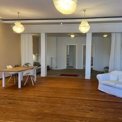 Heller, moderner Raum mit Holzboden, Möbeln und entspannter Atmosphäre.